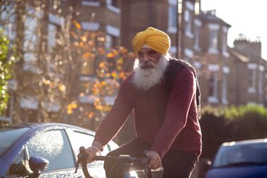An older sikh man riding a bicycle