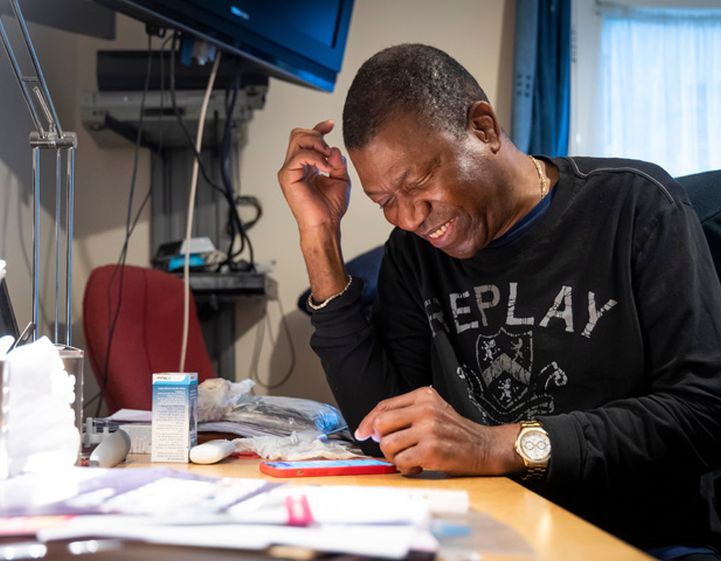 Smiling man sat a desk with papers sprawled across the desk studying for an exam.