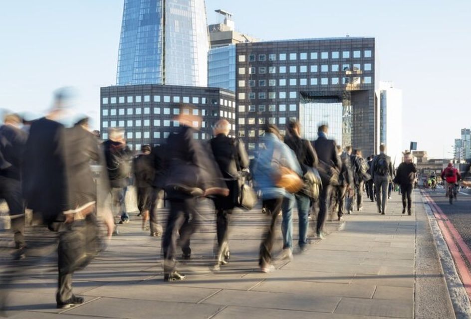 Blurred view of people walking across London Bridge on a sunny day, with the Shard building in the background