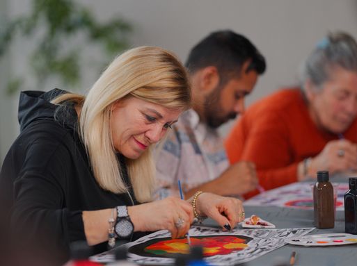 A white woman with blonde hair painting and smiling with a group.
