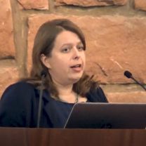 Aimee Stimpson, a white woman with brown hair speaking at a conference.