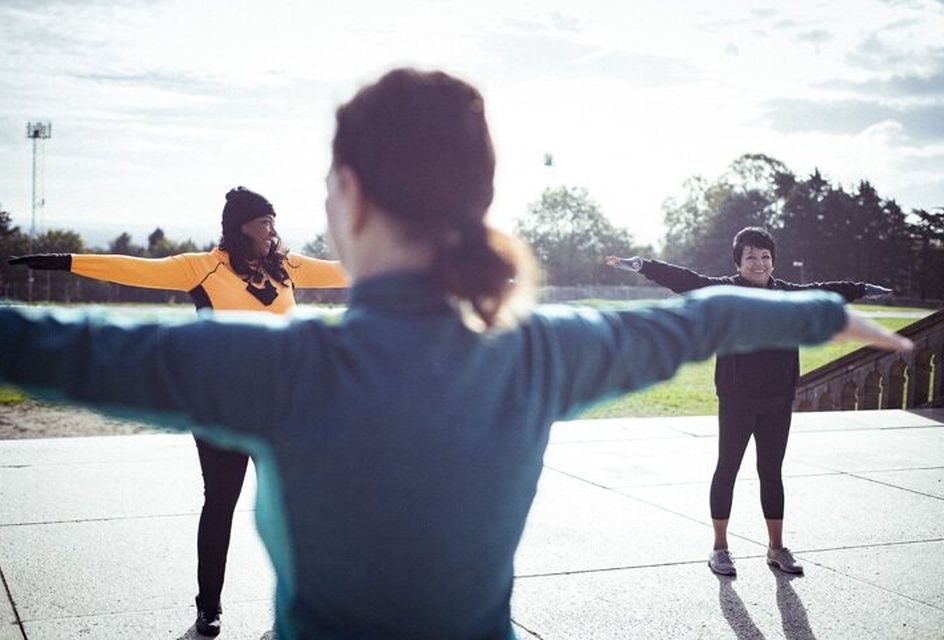 A group of three women stretching in a park