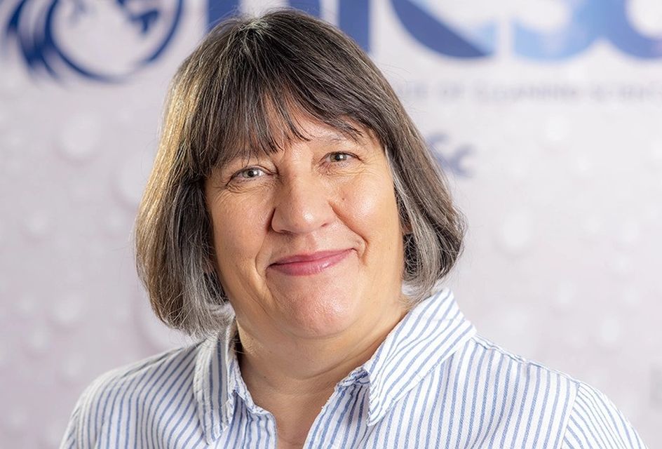 Denise Hanson, a white woman with short brown hair smiles at the camera