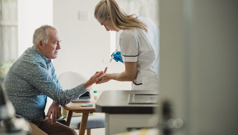 A nurse inspects the hand of an elderly man.
