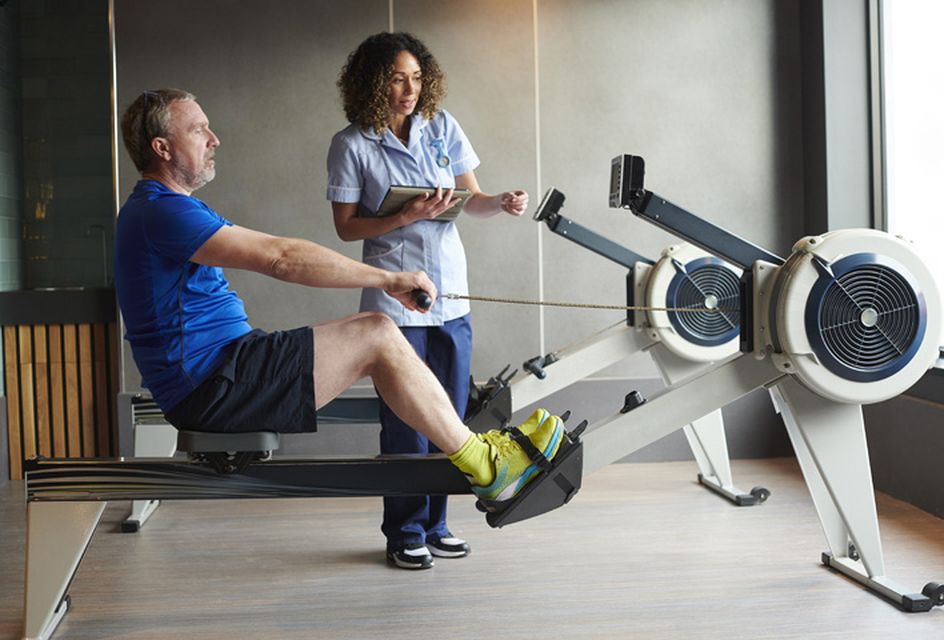 Female physical therapist helping a male patient to use an exercise machine