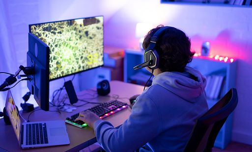 A teenager with headphones on plays videogames in his bedroom