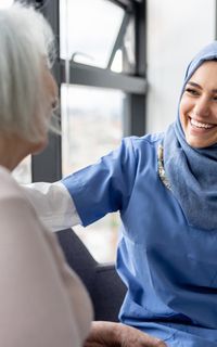 Healcare worker wearing a hijab laughing with an older woman patient, representation of the work of RSPH membership