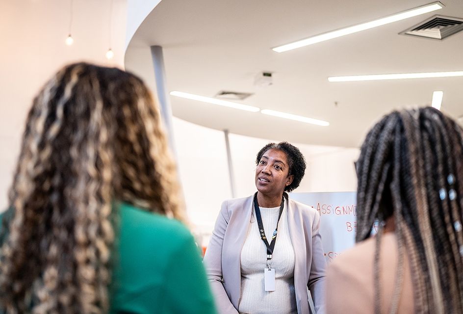 An older black teacher speaks to two of her students.