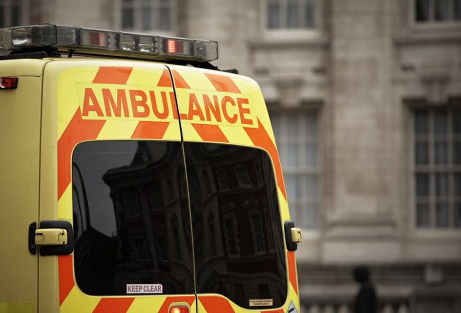The back of an ambulance with yellow and red stripes and text that reads "ambulance".