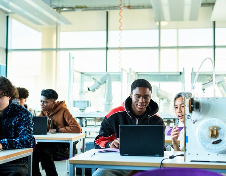 A room of students studying in a bright classroom.