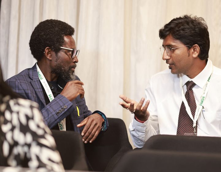 Two men talk at an RSPH event. They are both wearing RSPH lanyards.