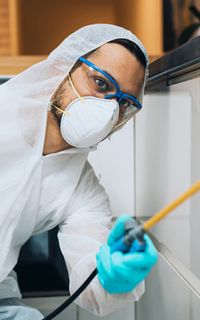 A pest management specialist spraying in a room