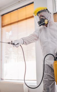 A pest management specialist spraying in a room
