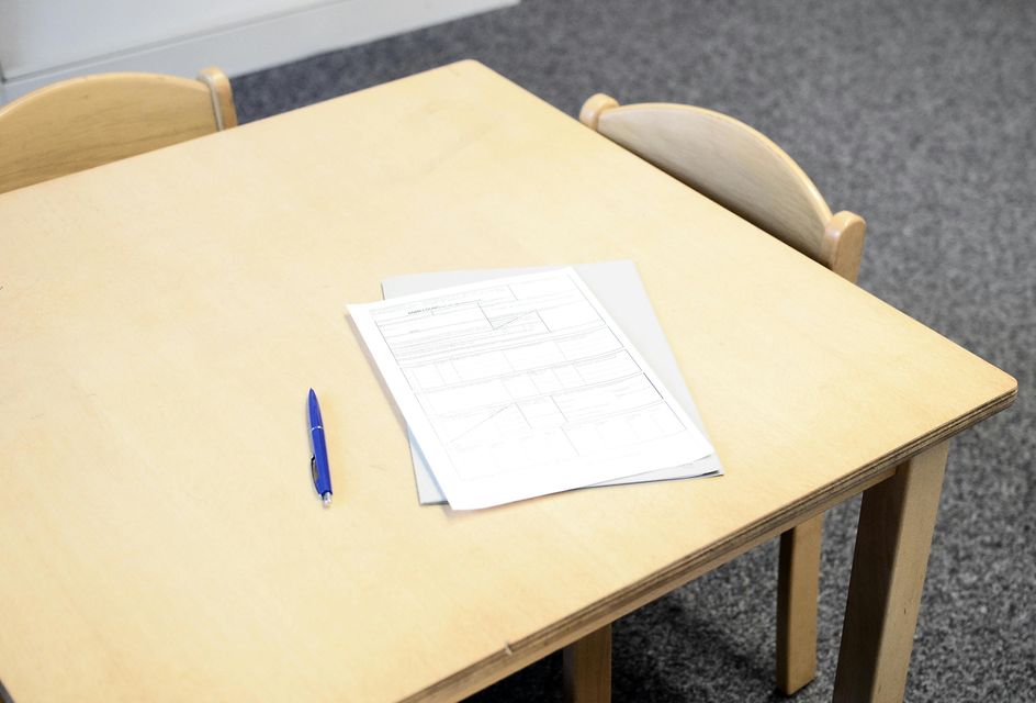 Wooden table with a pen and examination paper on it.