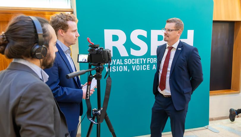 Man being interviewed by film crew behind RSPH banner at the 2024 Health & Wellbeing Awards