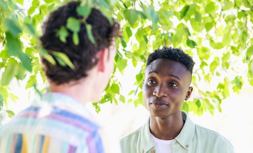 Two men talking under a tree